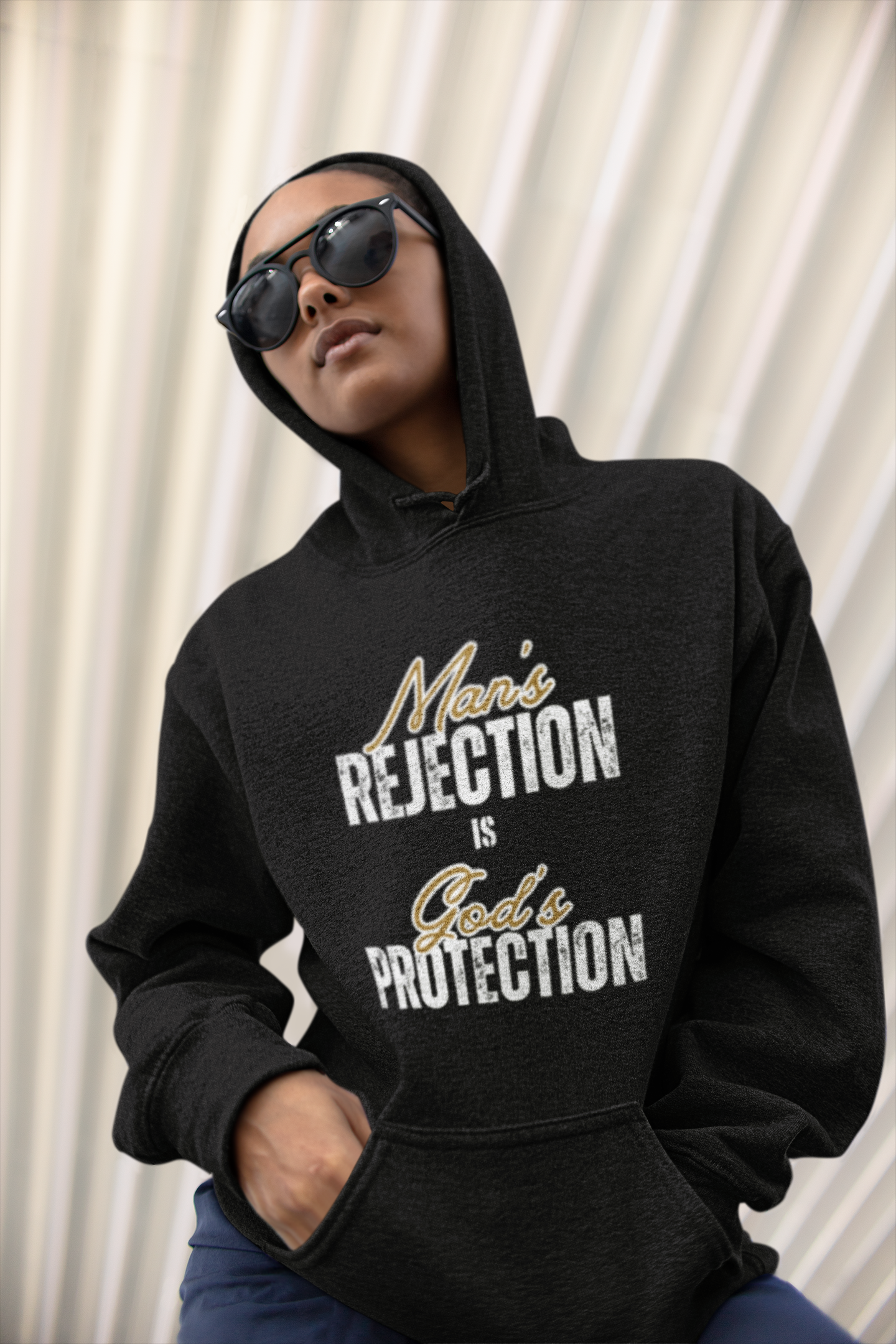 Christian Hoodie. Person wearing a black hoodie with text that reads  Man's Rejection is Gods Protection on  the front of  a the hoodie.