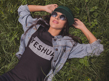 Christian T Shirt. Person wearing a denim jacket and sunglasses, lying on grass with 'YESHUA' shirt.